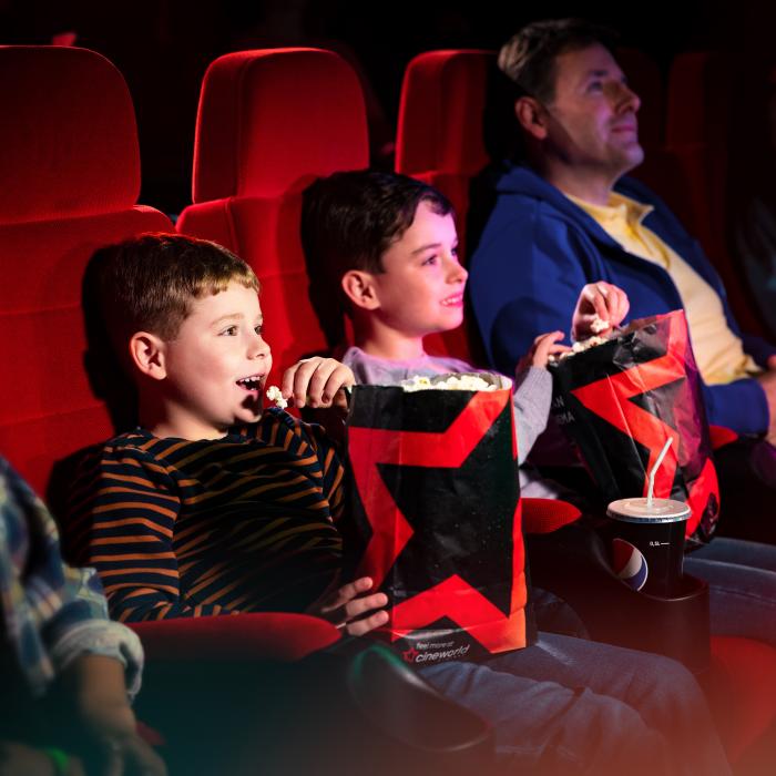 Children and Parent Watching a Film in Cinema Screen and Eating Popcorn