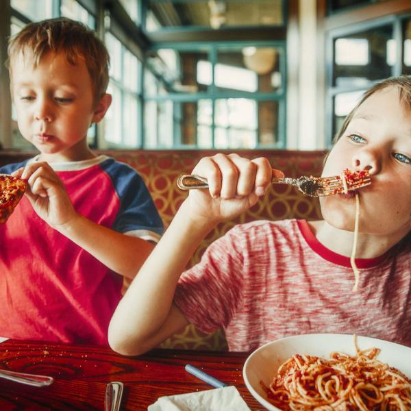 Two Children Eating Food in a Restaurant